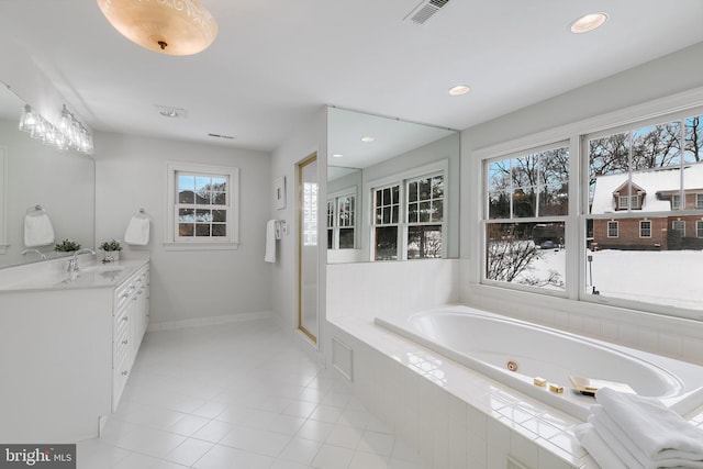 bathroom featuring tile patterned flooring, tiled tub, and vanity