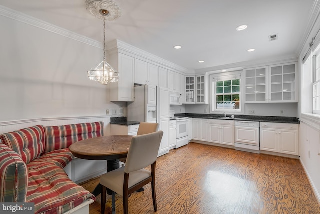 kitchen with white appliances, light hardwood / wood-style floors, sink, white cabinetry, and decorative light fixtures