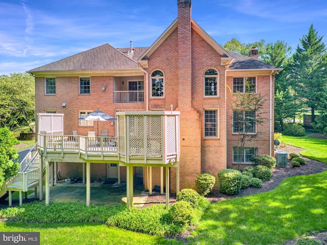 back of property with central AC unit, a deck, and a lawn