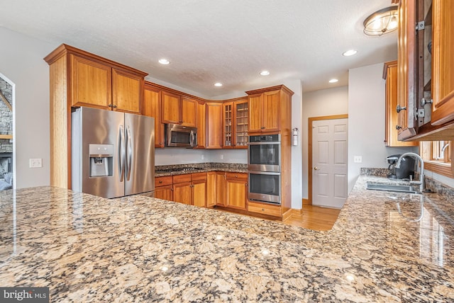 kitchen featuring a textured ceiling, sink, stainless steel appliances, and stone counters