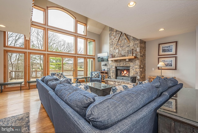 living room with a fireplace, plenty of natural light, high vaulted ceiling, and light hardwood / wood-style flooring