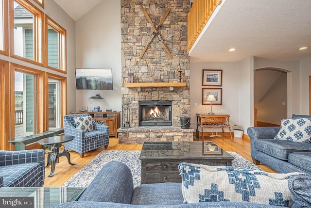 living room with a fireplace, hardwood / wood-style floors, high vaulted ceiling, and plenty of natural light