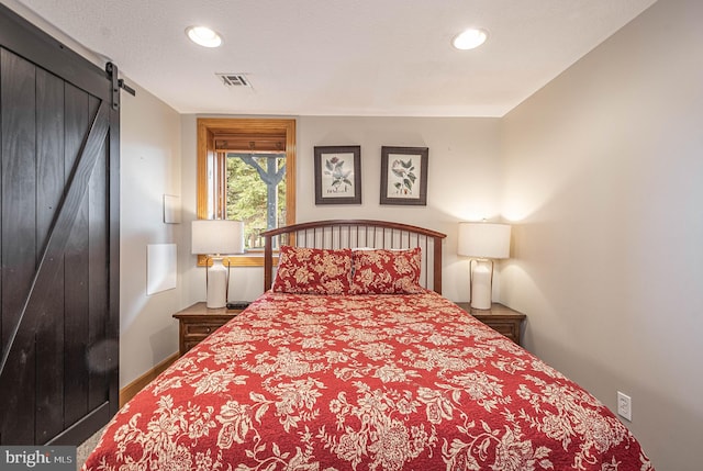 bedroom with a barn door and a textured ceiling