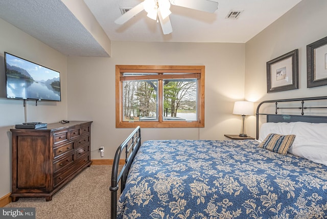 bedroom featuring a textured ceiling, ceiling fan, and light carpet