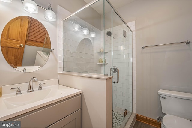 bathroom with vanity, toilet, a shower with shower door, and wood-type flooring