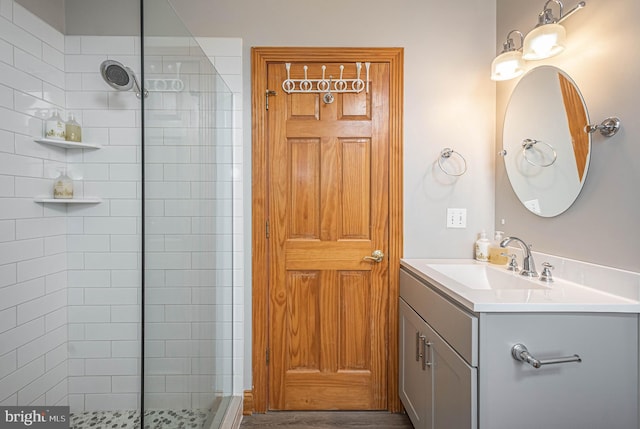 bathroom with hardwood / wood-style flooring, vanity, and a tile shower