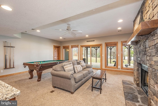 playroom featuring light carpet, a textured ceiling, a stone fireplace, and billiards