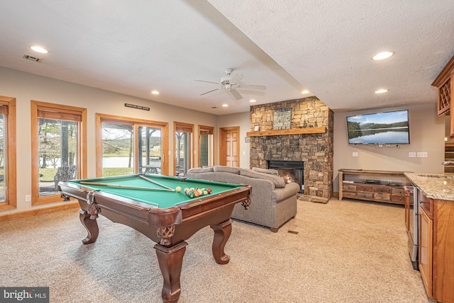 recreation room with a fireplace, a textured ceiling, pool table, and light carpet