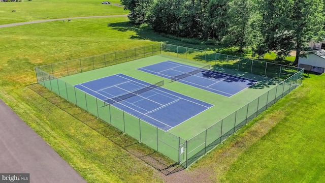 view of tennis court featuring a lawn and basketball hoop