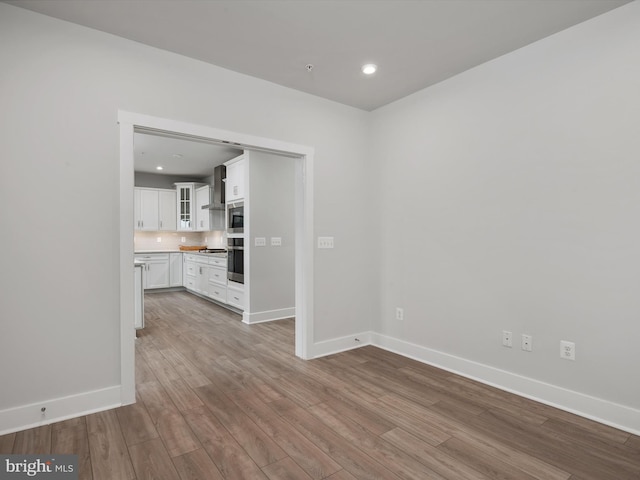 interior space with baseboards, wood finished floors, and recessed lighting