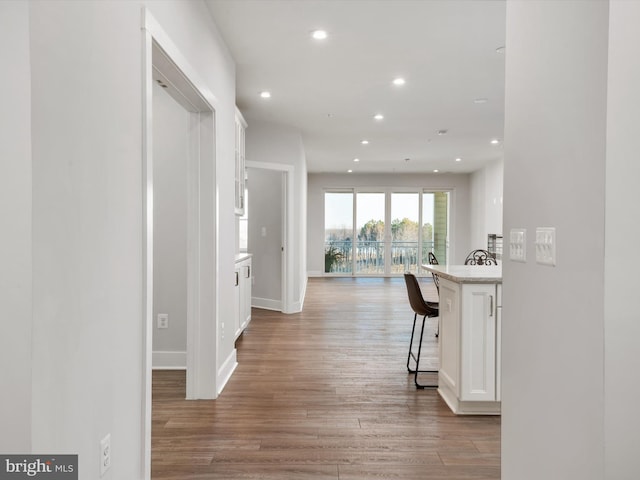 corridor with light wood-style floors, recessed lighting, and baseboards