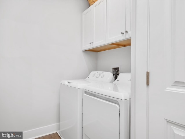 laundry area featuring hardwood / wood-style flooring, cabinets, and washing machine and dryer