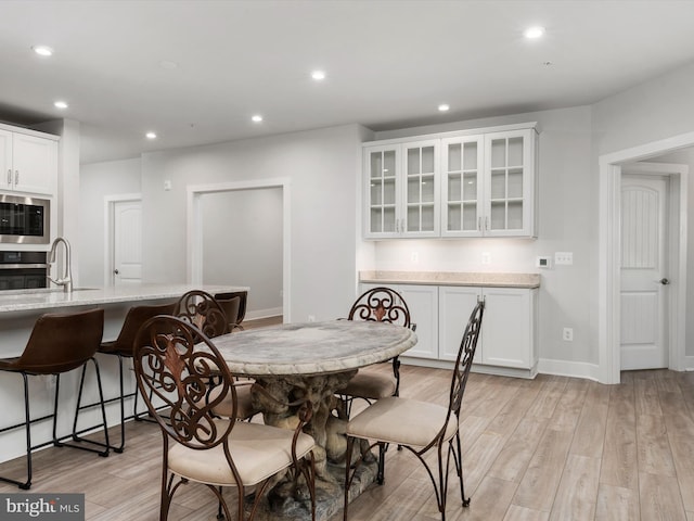 dining area with sink and light hardwood / wood-style floors