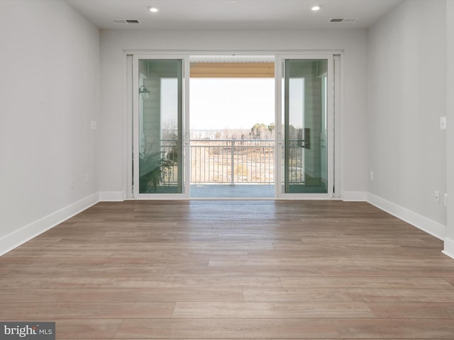 spare room with baseboards, visible vents, and light wood finished floors