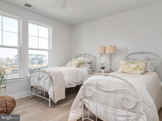 bedroom featuring light wood finished floors, a ceiling fan, visible vents, and baseboards