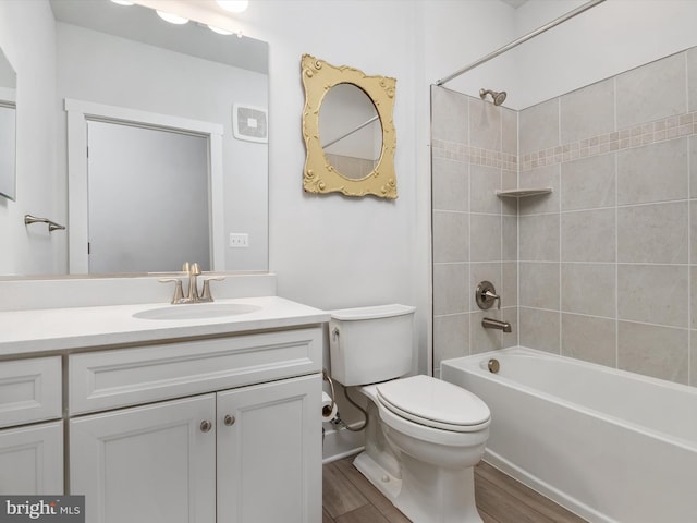 full bathroom featuring hardwood / wood-style flooring, tiled shower / bath, vanity, and toilet