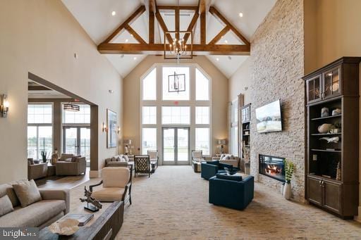 carpeted living area featuring a chandelier, french doors, high vaulted ceiling, and a stone fireplace