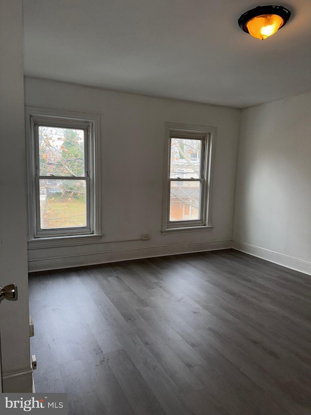 empty room with dark wood-type flooring and a healthy amount of sunlight