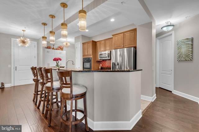 kitchen featuring backsplash, sink, hanging light fixtures, dark hardwood / wood-style floors, and appliances with stainless steel finishes