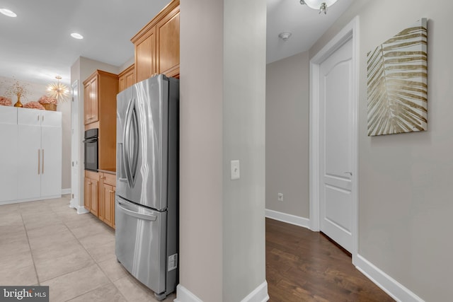 kitchen featuring black oven, stainless steel fridge with ice dispenser, and light hardwood / wood-style floors