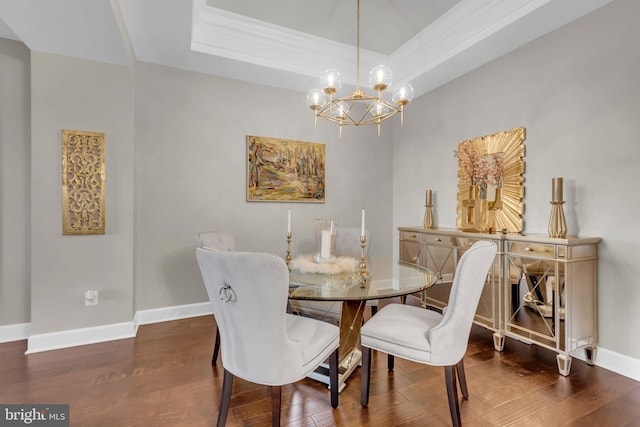 dining room with a raised ceiling, dark hardwood / wood-style flooring, ornamental molding, and an inviting chandelier