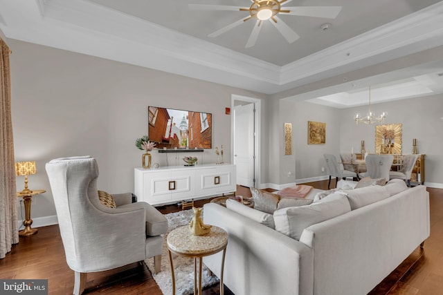 living room featuring ceiling fan with notable chandelier, dark hardwood / wood-style flooring, crown molding, and a tray ceiling