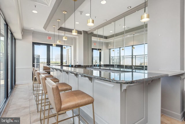 1915 Towne Centre Blvd Unit 416, Annapolis, MD 21401 - kitchen featuring ornamental molding, a breakfast bar, light tile patterned flooring, dark stone countertops, and decorative light fixtures
