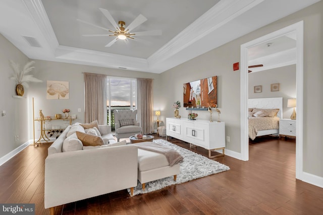 living room with a tray ceiling, crown molding, dark hardwood / wood-style flooring, and ceiling fan