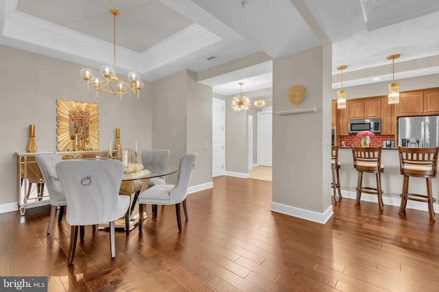 dining space with hardwood / wood-style floors, a notable chandelier, a raised ceiling, and ornamental molding