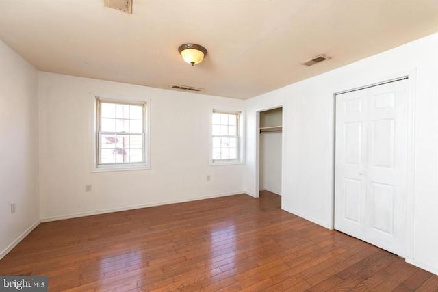 unfurnished bedroom with dark wood-type flooring and multiple closets