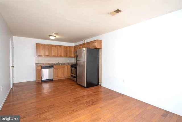 kitchen with appliances with stainless steel finishes, dark hardwood / wood-style flooring, tasteful backsplash, and sink