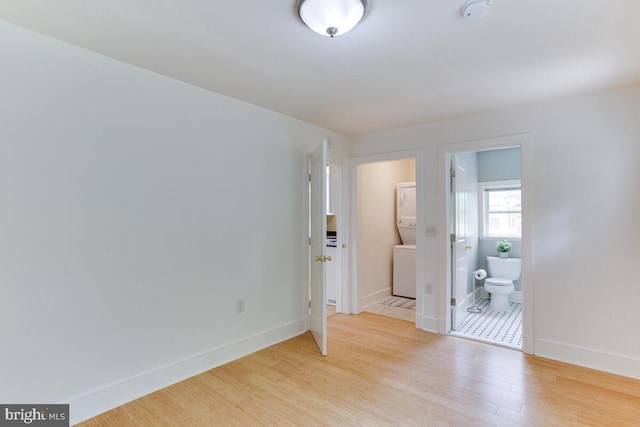 interior space featuring ensuite bath, stacked washer and dryer, and light wood-type flooring