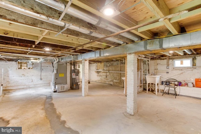 basement featuring gas water heater, heating unit, and sink