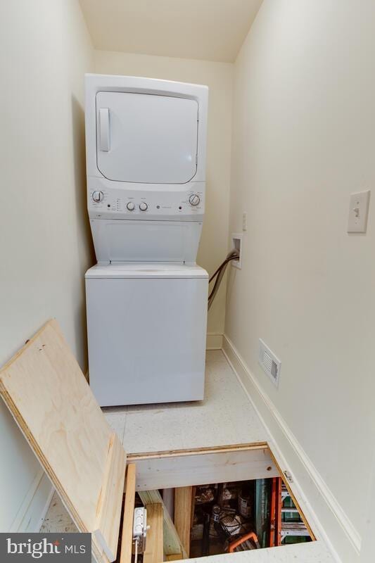 clothes washing area featuring stacked washer and clothes dryer