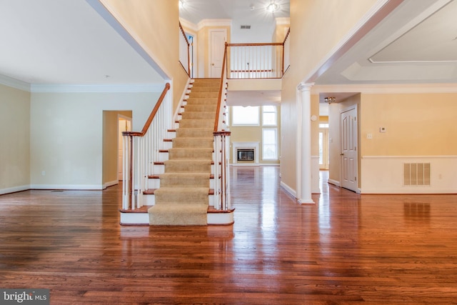 foyer featuring a high ceiling, ornamental molding, dark hardwood / wood-style flooring, and decorative columns