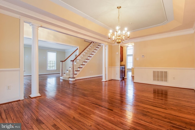 empty room featuring a notable chandelier, a wealth of natural light, ornamental molding, and hardwood / wood-style flooring