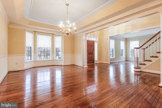 interior space with an inviting chandelier, ornamental molding, hardwood / wood-style floors, and a tray ceiling