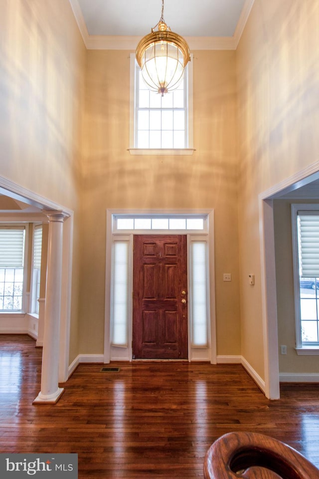 foyer with dark wood-type flooring, a high ceiling, and decorative columns