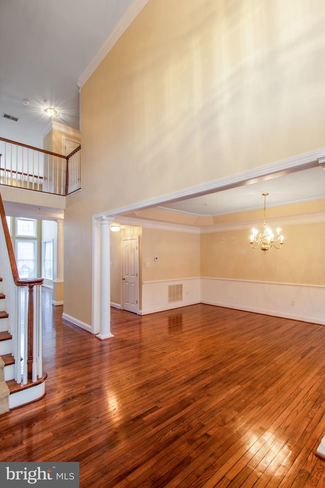 unfurnished living room with hardwood / wood-style floors, a chandelier, and ornamental molding