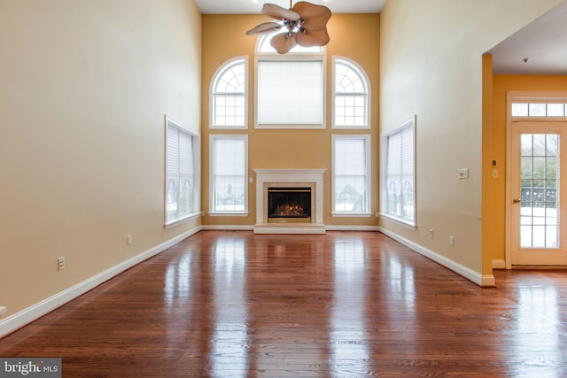 unfurnished living room with ceiling fan, wood-type flooring, and plenty of natural light