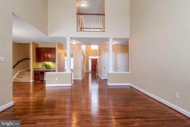 unfurnished living room featuring dark hardwood / wood-style flooring and a towering ceiling