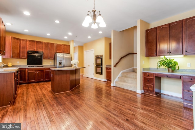 kitchen featuring a kitchen island, black double oven, hanging light fixtures, stainless steel fridge, and a notable chandelier