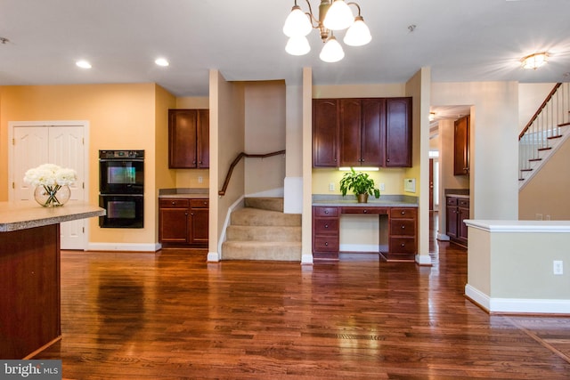 kitchen with black double oven, pendant lighting, dark hardwood / wood-style floors, and a notable chandelier