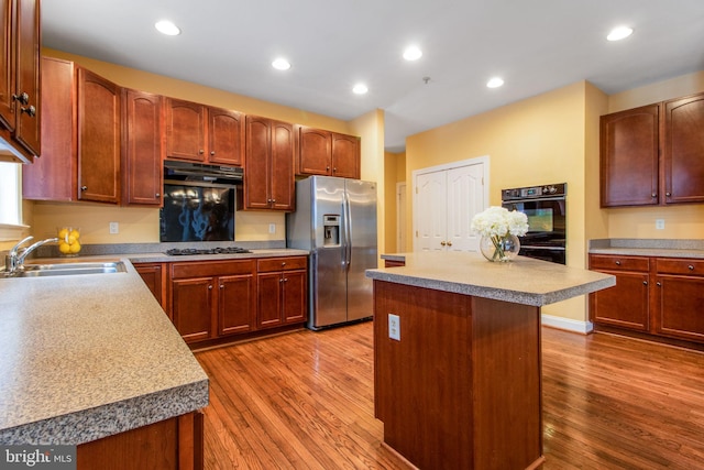 kitchen with hardwood / wood-style floors, a center island, sink, stainless steel fridge with ice dispenser, and black double oven