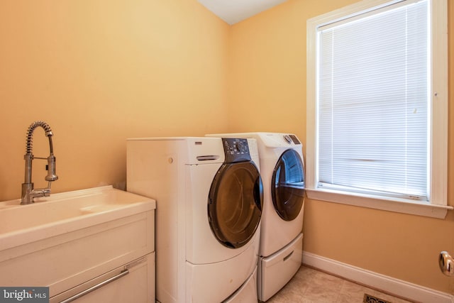 washroom with light tile patterned floors, washing machine and dryer, and sink