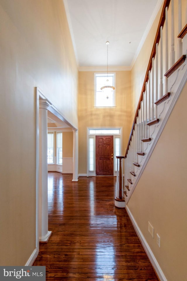 entryway featuring ornamental molding, a towering ceiling, and dark hardwood / wood-style floors