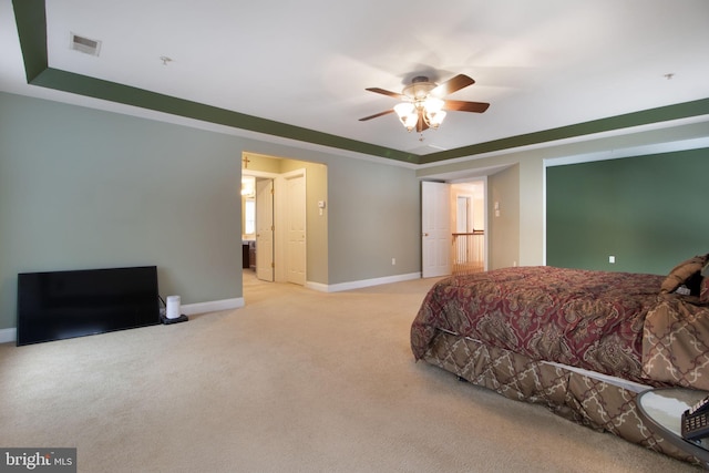 bedroom featuring ceiling fan, a tray ceiling, and light carpet