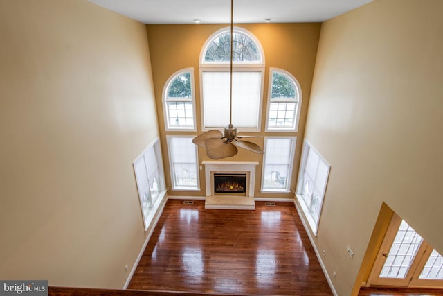 unfurnished living room featuring ceiling fan, a towering ceiling, and dark hardwood / wood-style flooring