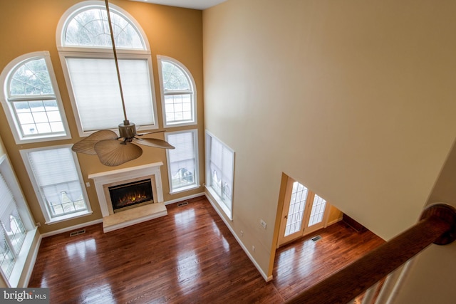 unfurnished living room featuring ceiling fan, a high ceiling, and dark hardwood / wood-style floors