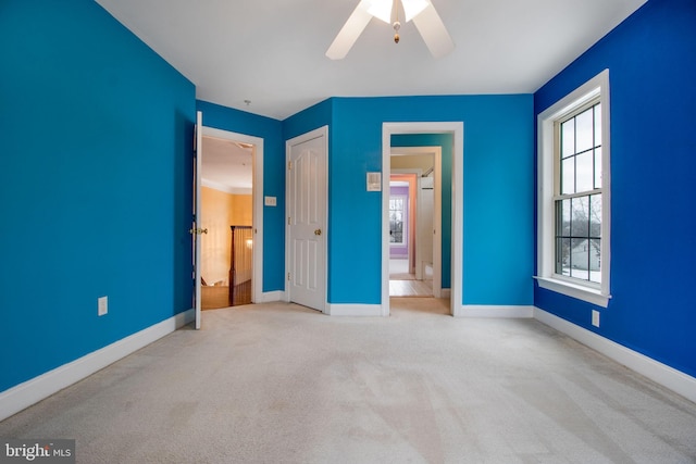 unfurnished bedroom with ceiling fan, light colored carpet, multiple windows, and a closet